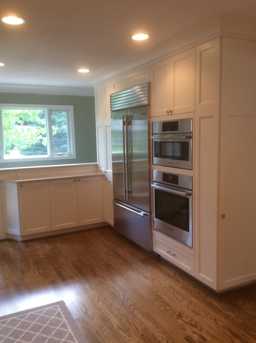 Kitchen remodel with white cabinetry, built-in Sub-Zero refrigerator, and double wall ovens