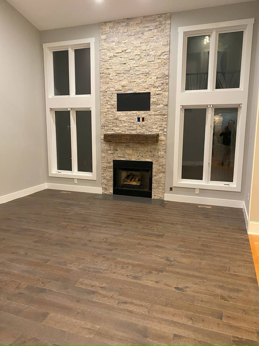 Two-story living room with floor-to-ceiling stacked stone fireplace and reclaimed-wood mantel