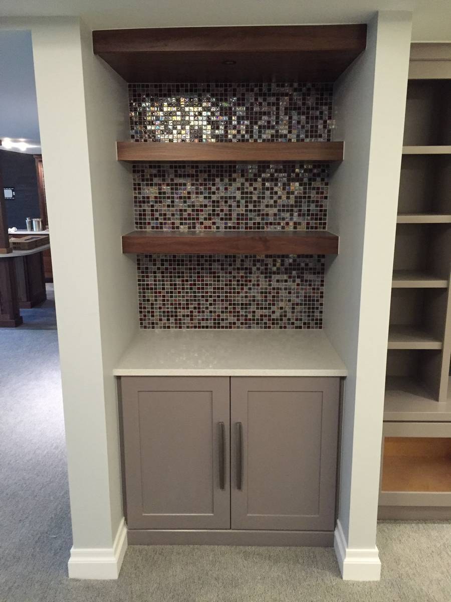 Basement bar built-in with iridescent glass mosaic backsplash and walnut floating shelves