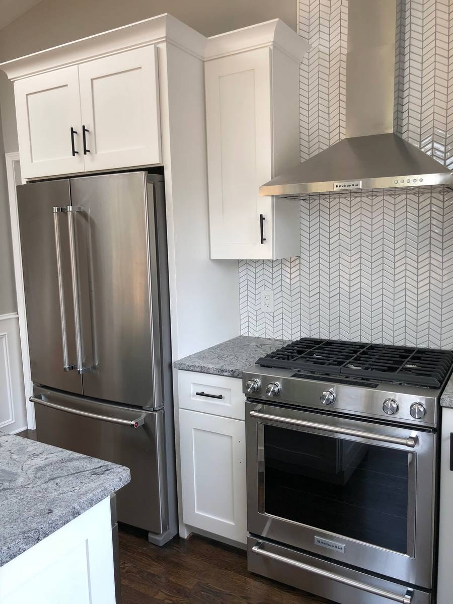 White shaker kitchen with chevron herringbone backsplash and KitchenAid professional range