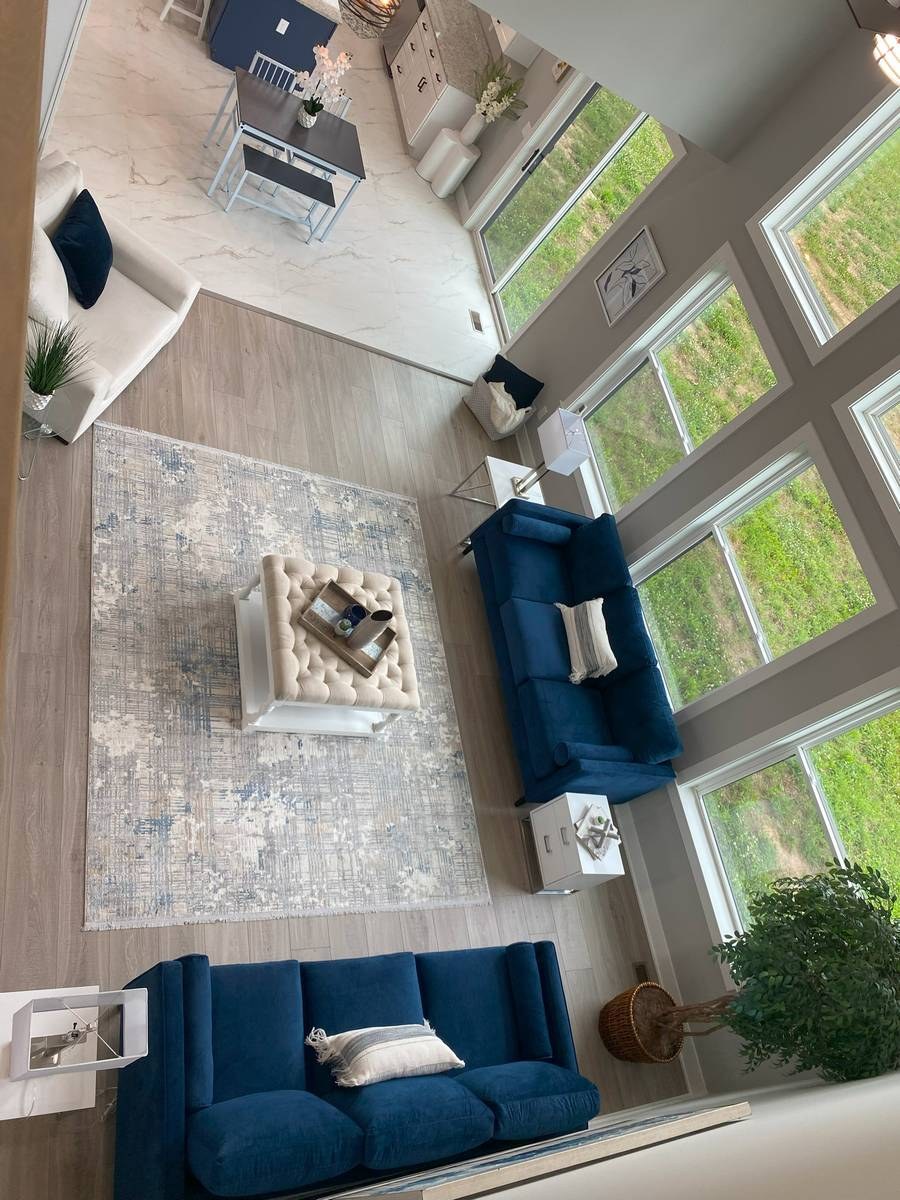 Great room with vaulted ceiling, timber detail, and wide-plank hardwood flooring in custom new build