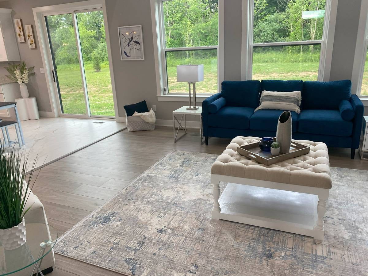 Open great room with sliding glass doors, blue sofa, and views to backyard