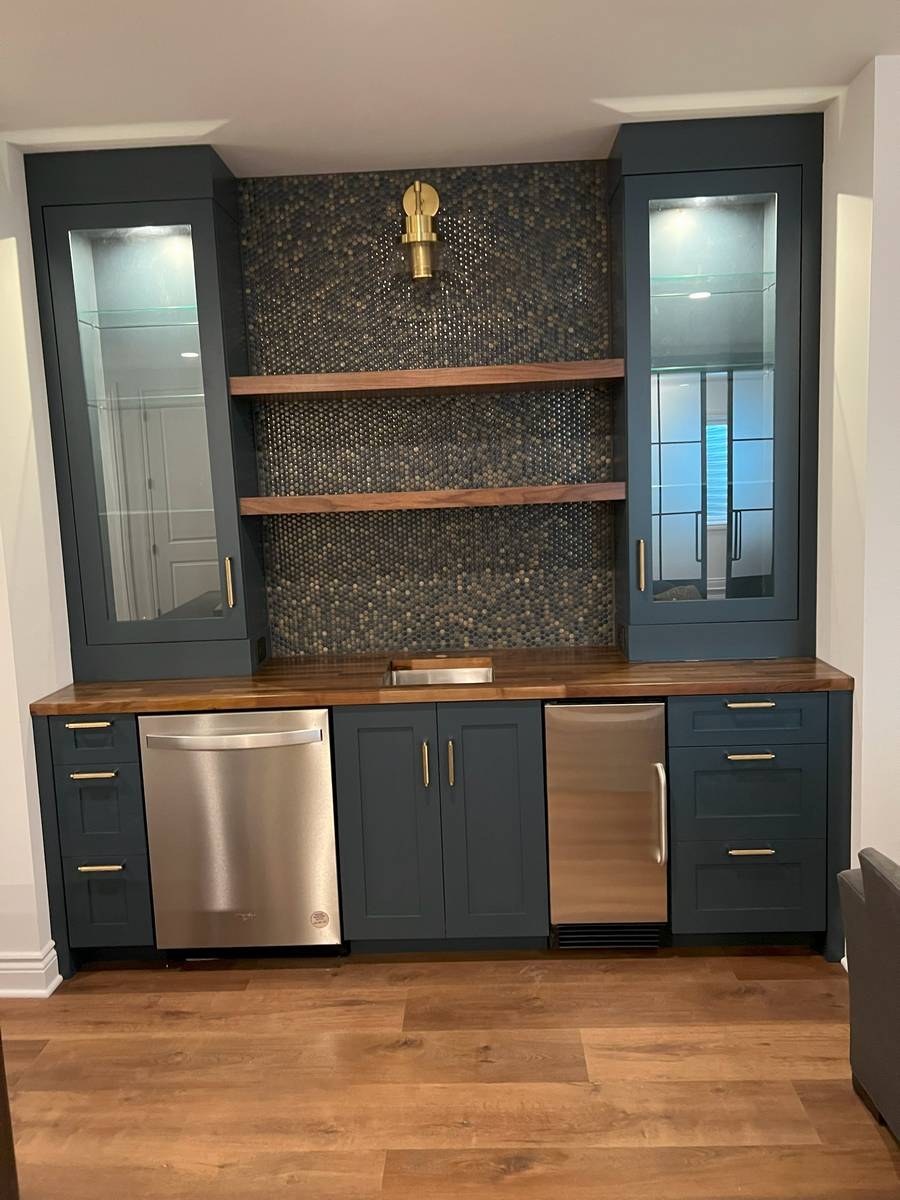 Navy blue wet bar with penny-round mosaic backsplash, walnut counters, and brass fixtures
