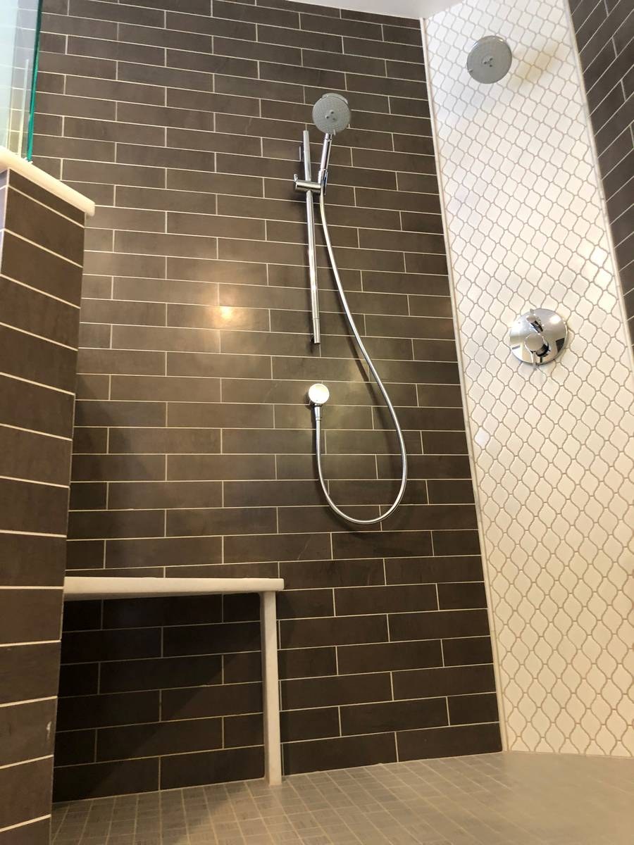 Walk-in shower close-up with dark subway tile and handheld shower head