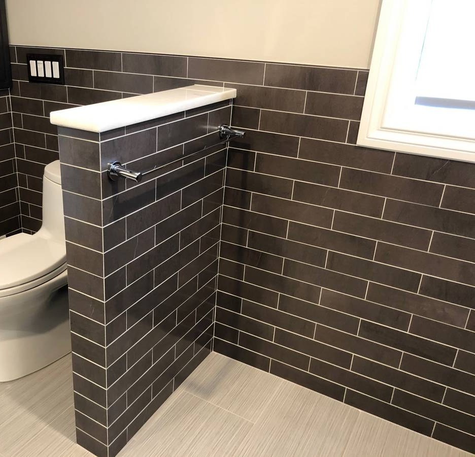 Bathroom corner showing dark subway tile knee-wall and vanity cabinetry