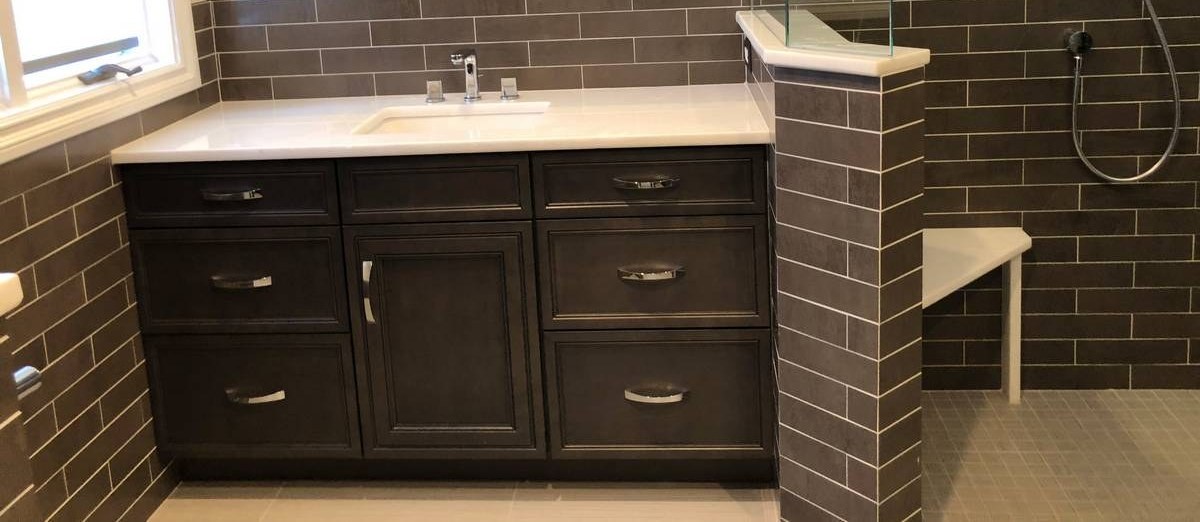 Single vanity with dark shaker cabinet, white quartz, and open walk-in shower beyond