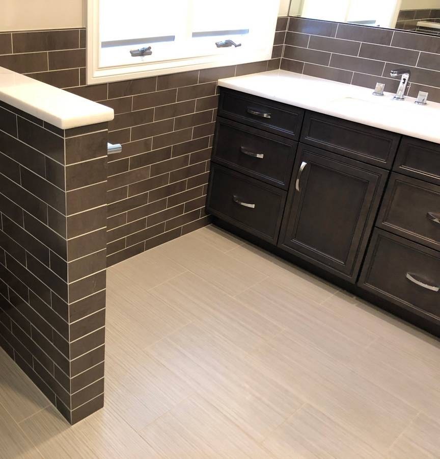 Bathroom knee-wall and vanity with dark subway tile throughout