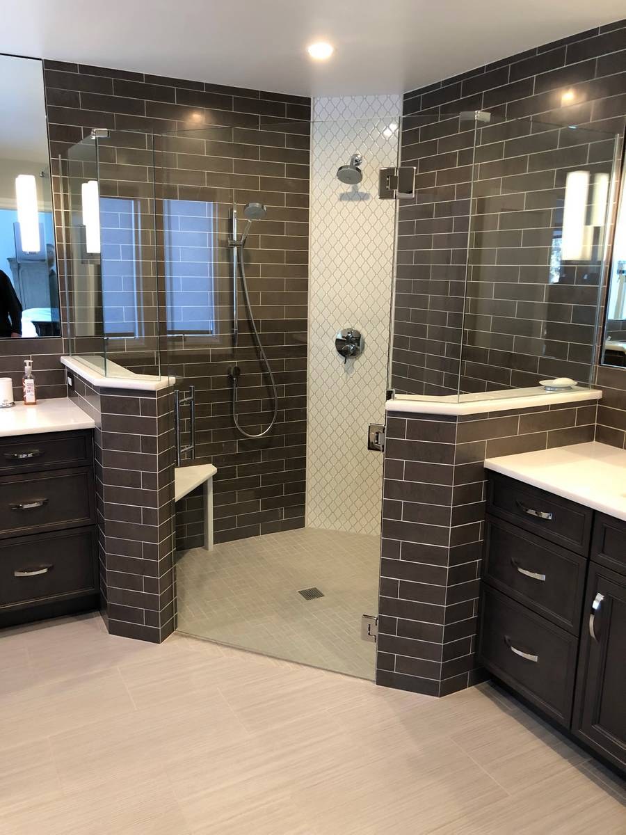 Primary bath with dual dark shaker vanities, full-wall subway tile, and open walk-in shower