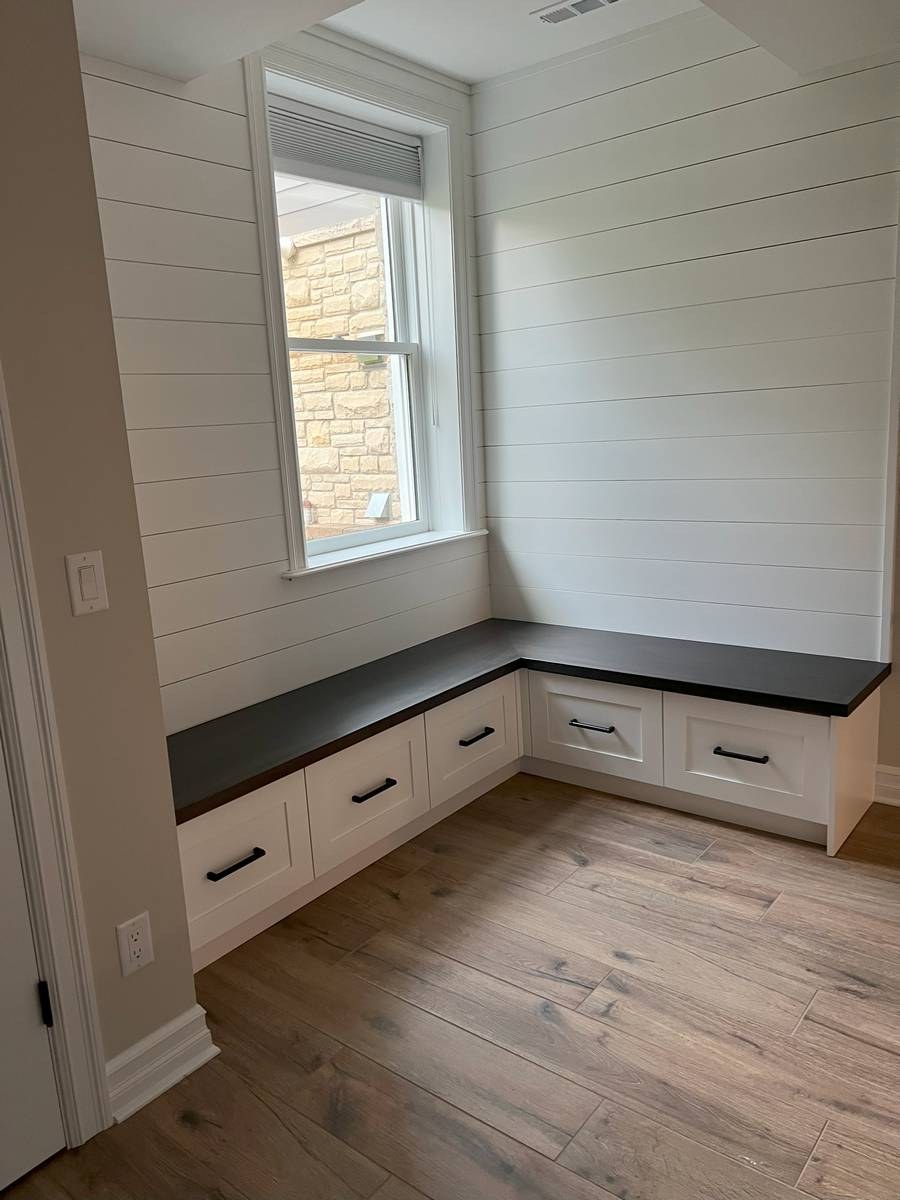 Mudroom bench with shiplap accent wall, white cabinetry, and built-in storage
