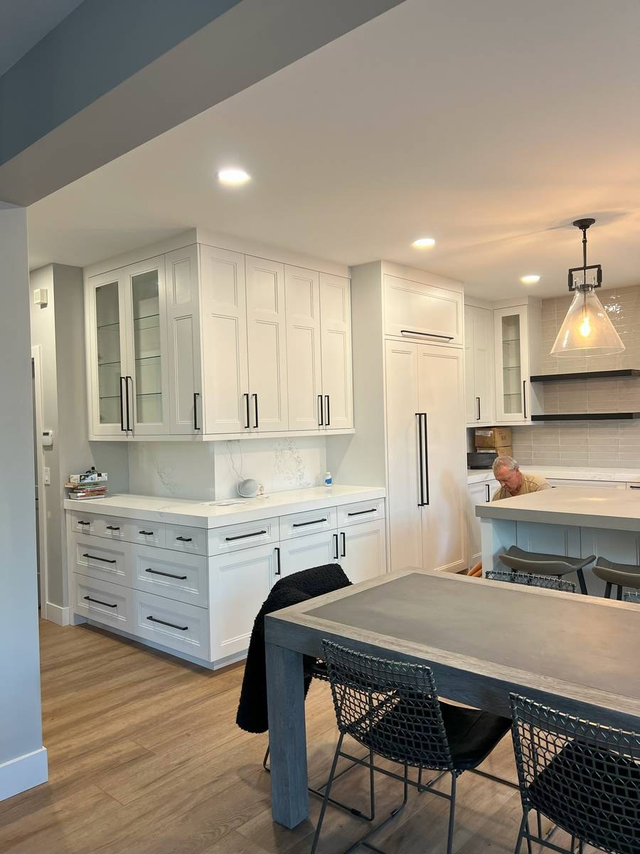 Transitional white kitchen with paneled refrigerator, concrete waterfall island, and floating shelves