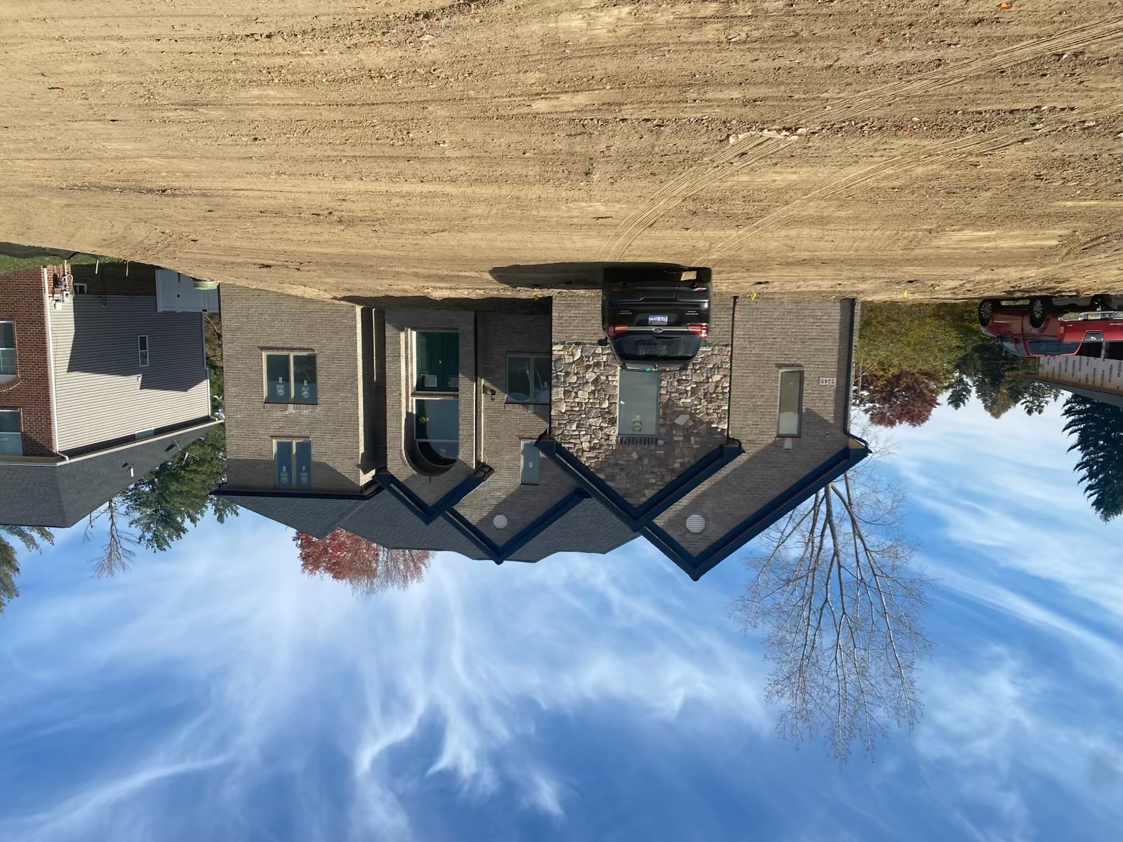 Completed custom ranch-style home with stone and brick exterior under autumn sky