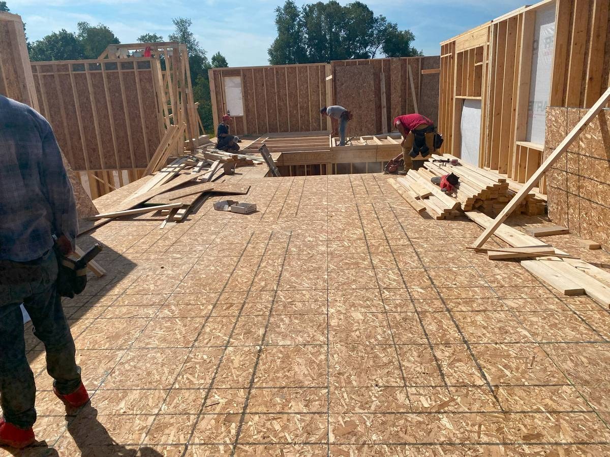 Construction crew framing walls and floor system on custom new home build