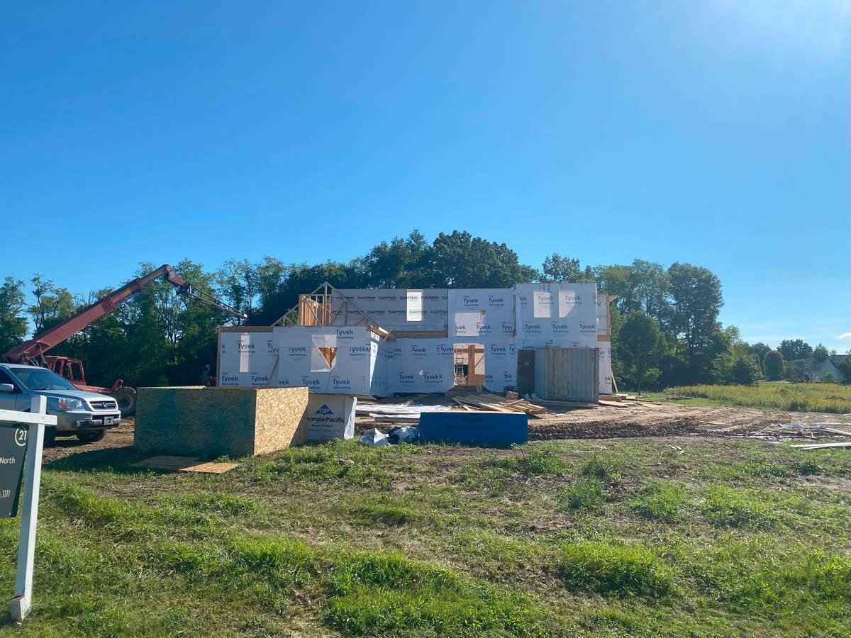 Tyvek-wrapped two-story custom home with crane on site during construction