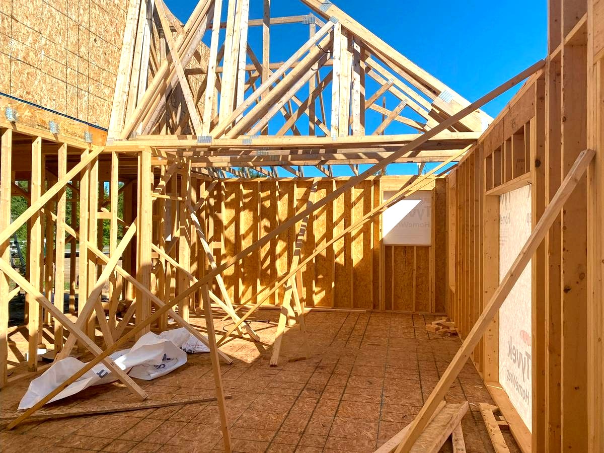 Interior view of custom home framing with roof trusses set against blue sky