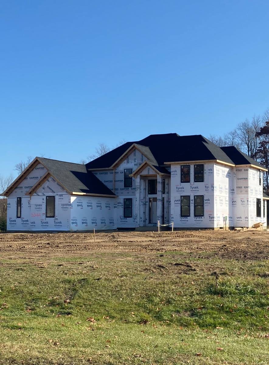 Large two-story custom home at lockup stage, fully framed and roofed