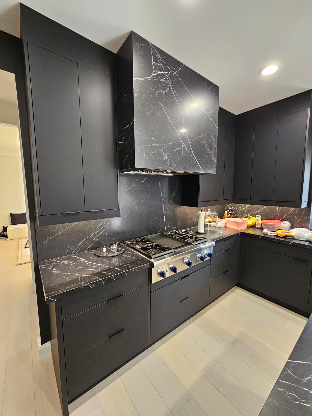 Modern dark kitchen with floor-to-ceiling black cabinetry and built-in double wall ovens