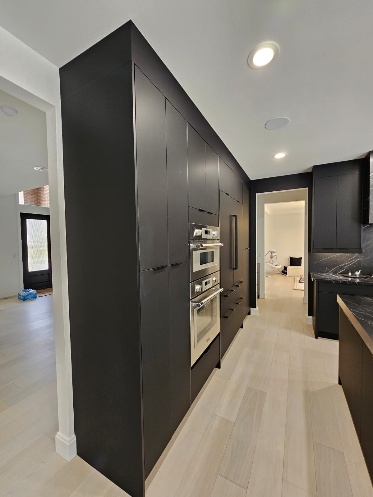 Sleek dark kitchen with marble hood, gas range, and black cabinetry